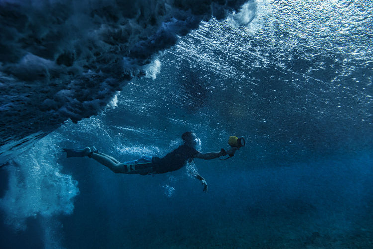 Man snorkeling while filming underwater at maldives