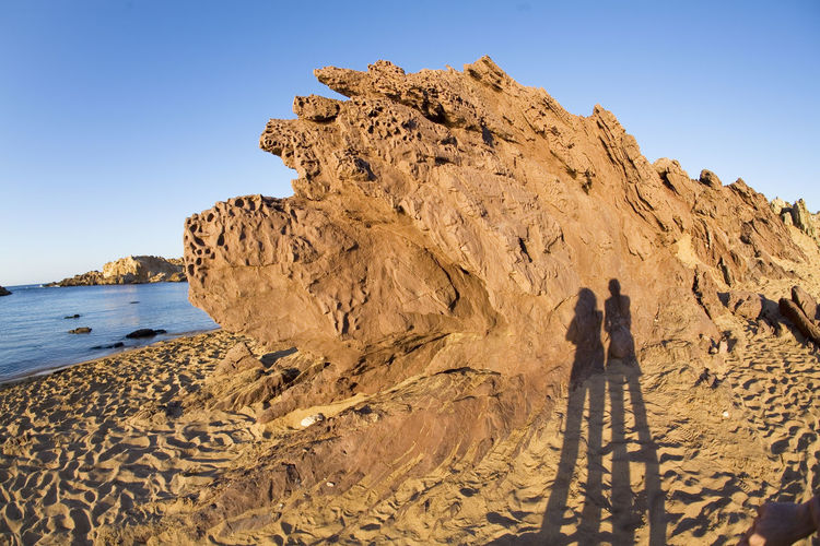Shadow of a couple on a rock formation on the beach