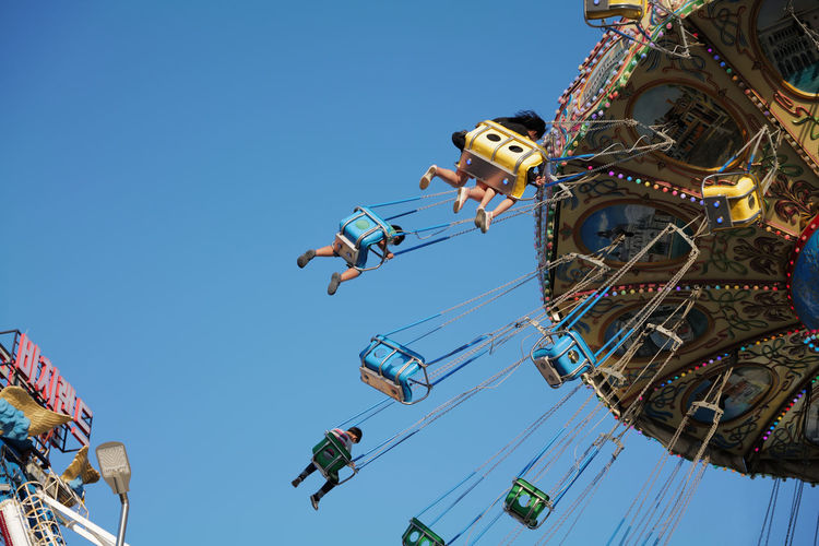Low angle view of a family and kids riding ferris wheel against clear blue sky