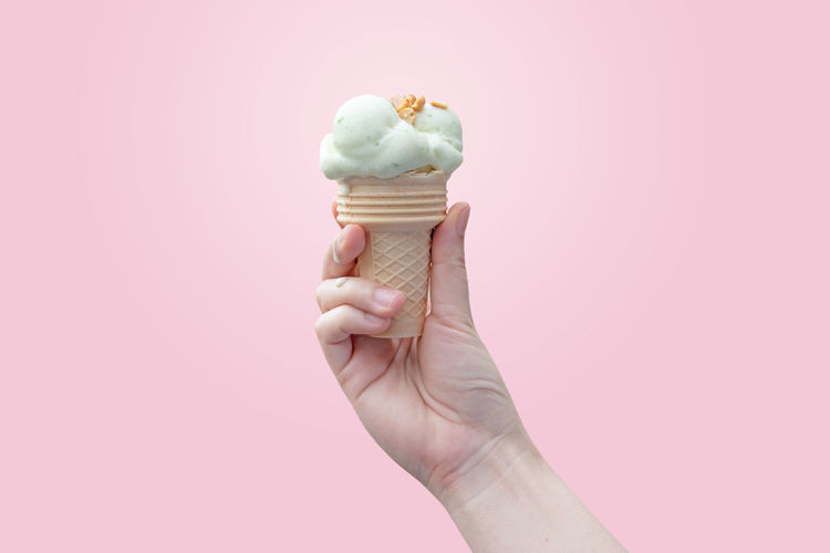 Hand holding ice cream cone against gray background