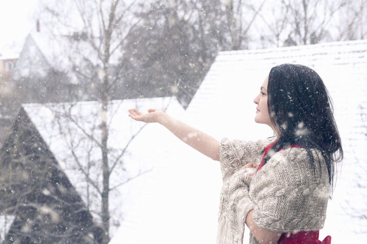 Side view of young woman enjoying snowfall