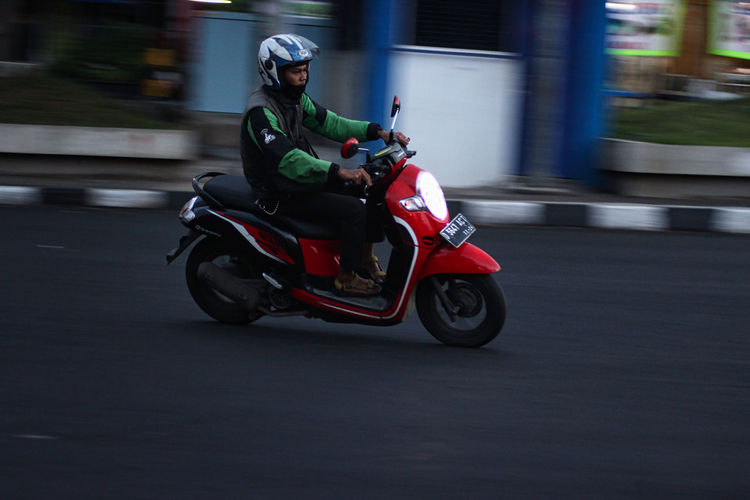Blurred motion of person riding motorcycle on road