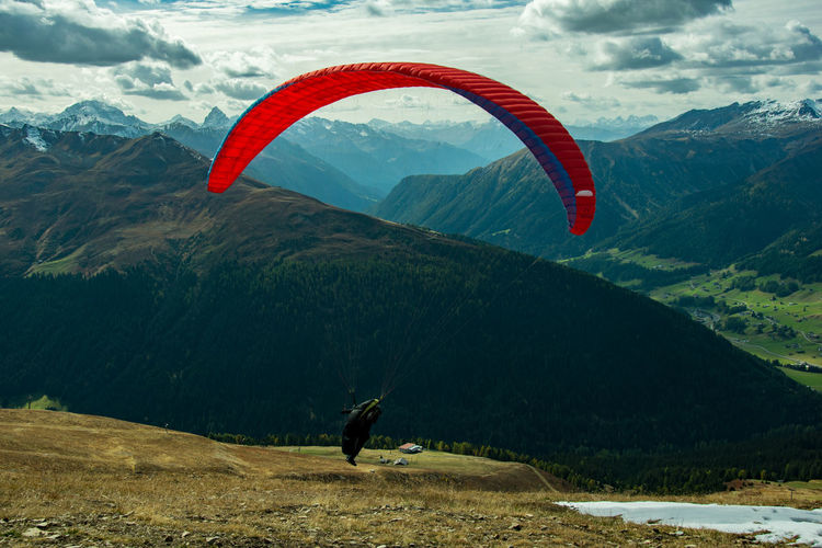 Man paragliding over mountain against sky
