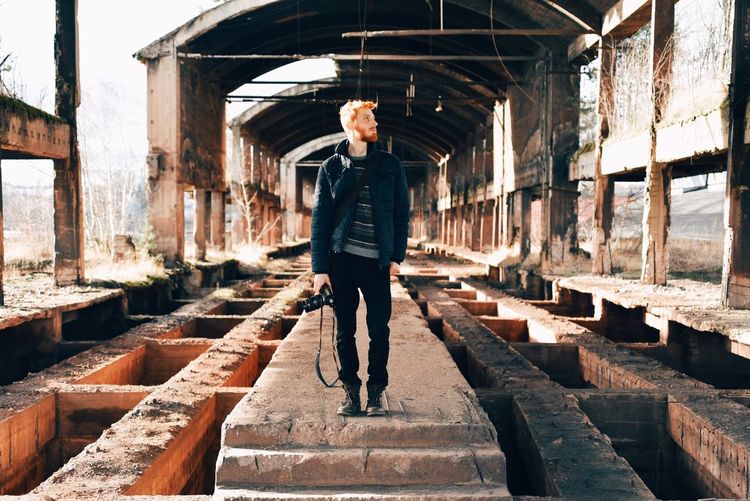 Full length of photographer standing in abandoned factory