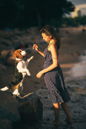 Woman standing by dog at beach against sky