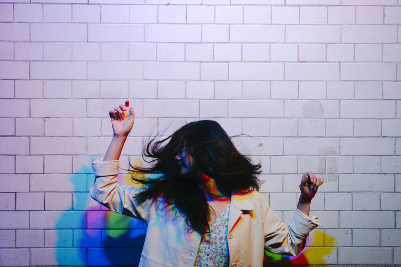 Young woman dancing in front of wall