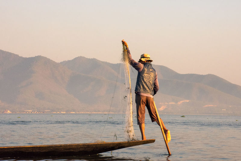 Fisherman balancing and fishing during sunset