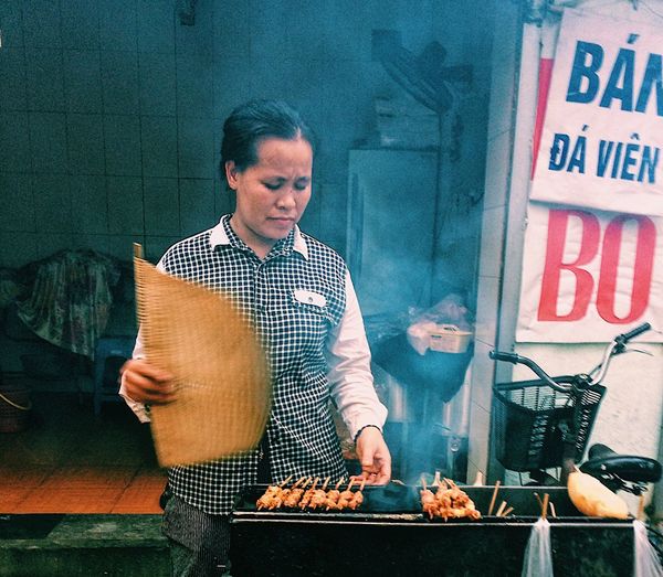Female vendor selling barbecue meat on street