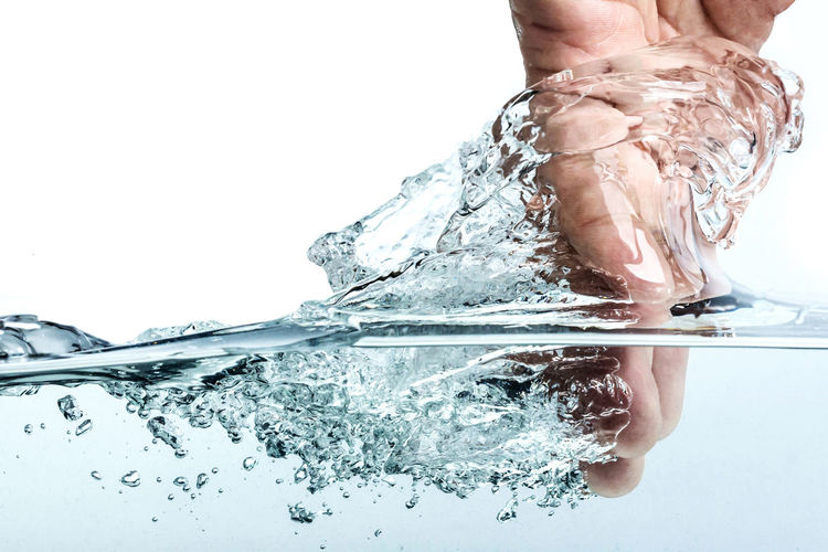 Close-up of person splashing water against white background