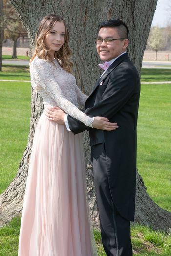 Portrait of well dressed couple embracing by tree 
