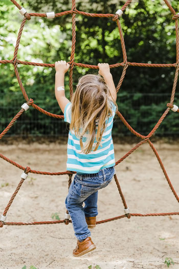 Rear view of girl playing on rope at playground