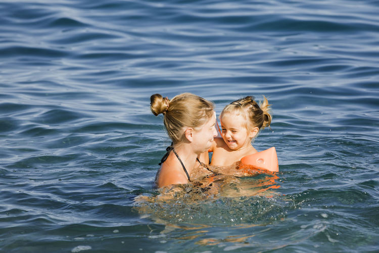 Rear view of mother with daughter in water