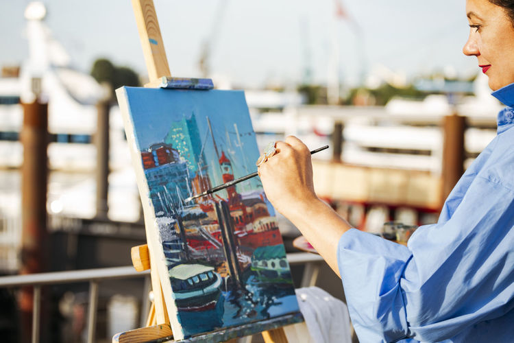 Smiling woman painting on canvas