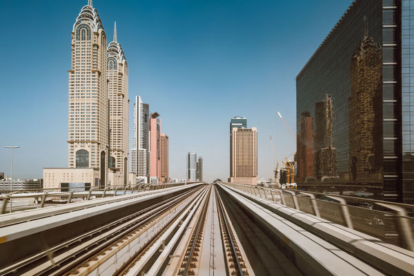 Railroad tracks by buildings against clear sky