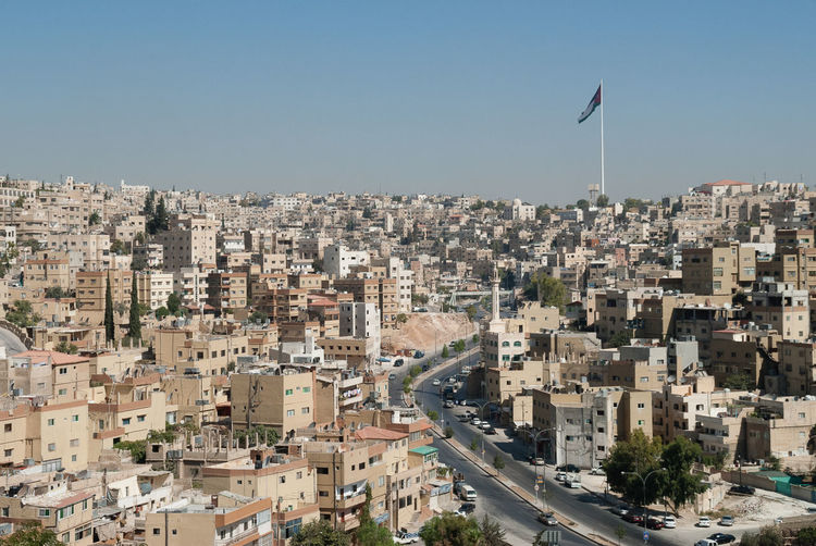 Large flag pole and flag and buildings in amman skyline, jordan