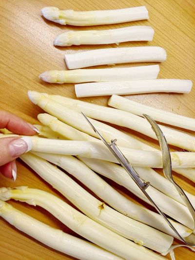 Cropped image of woman hand cutting white asparagus
