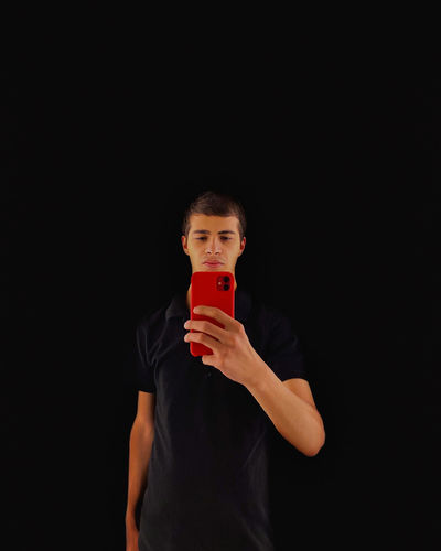 Man holding mobile phone against black background