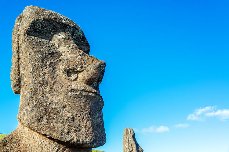 Low angle view of moai statue at easter island against blue sky