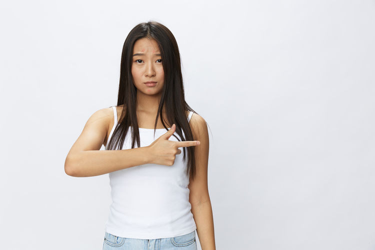 Portrait of young woman standing against white background