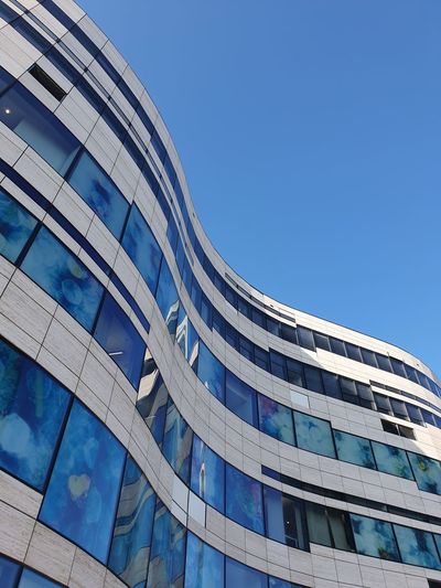 Low angle view of modern building against clear blue sky