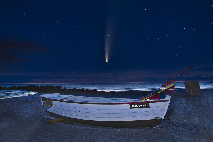 Boat moored on beach against sky at night