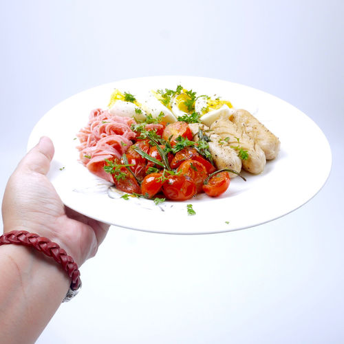Close-up of hand holding food over white background
