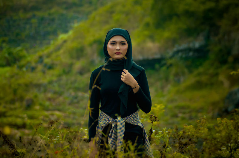 Portrait of young woman standing on field