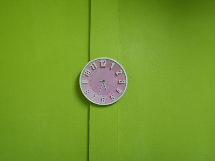 Close-up of clock on green wall