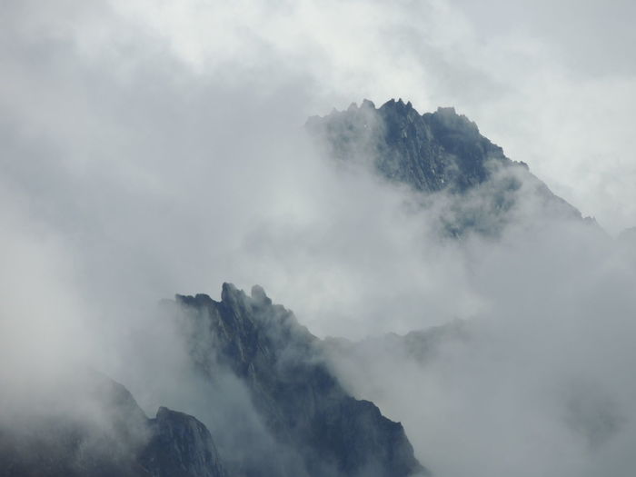 Scenic view of snow covered mountains against sky during foggy weather