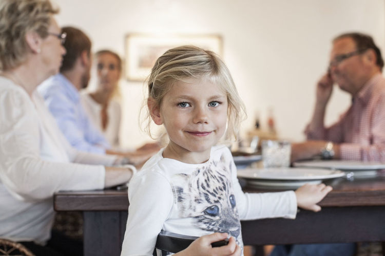 Portrait of girl sitting with family at dining table