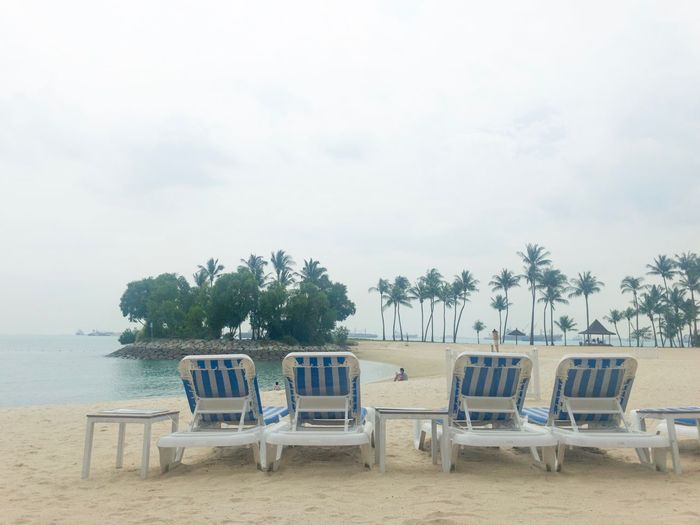 Chairs and table at beach against sky