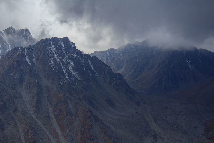 Mountain peaks in a gorge with thick dark clouds in autumn