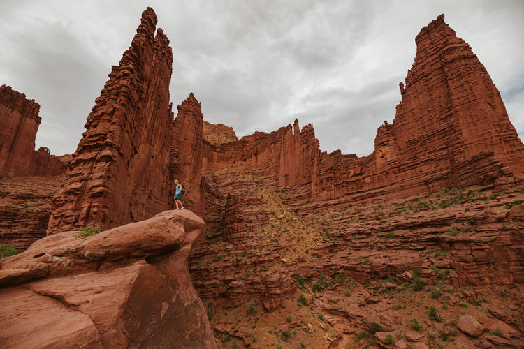 Fisher towers of red sandstone rise above a male hiker near moab utah