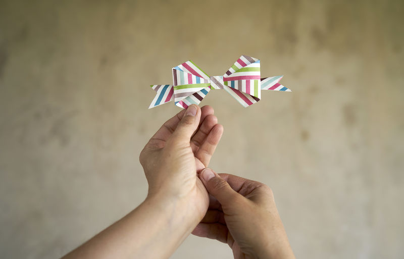 Hands holding gift bow made of colored paper