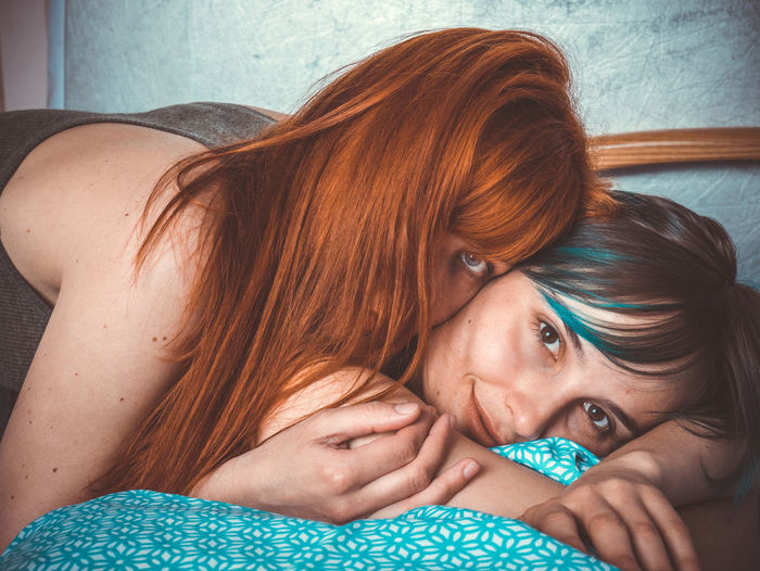 Portrait of lesbian couple lying on bed at home