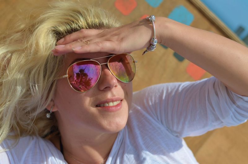 Smiling woman wearing sunglasses shielding eyes at park