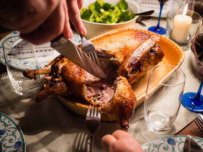 Midsection of man cutting roast turkey on table for christmas
