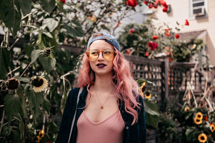 Young woman early twenties with pink hair strolls through sunflowers
