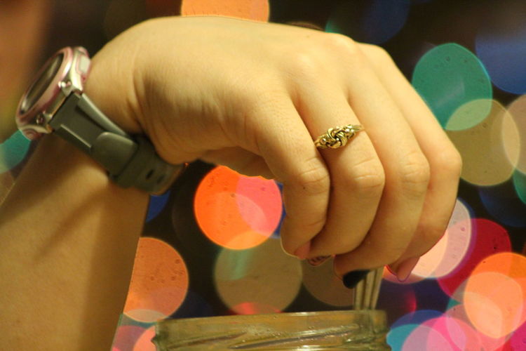 Cropped hand of woman against illuminated lens flare