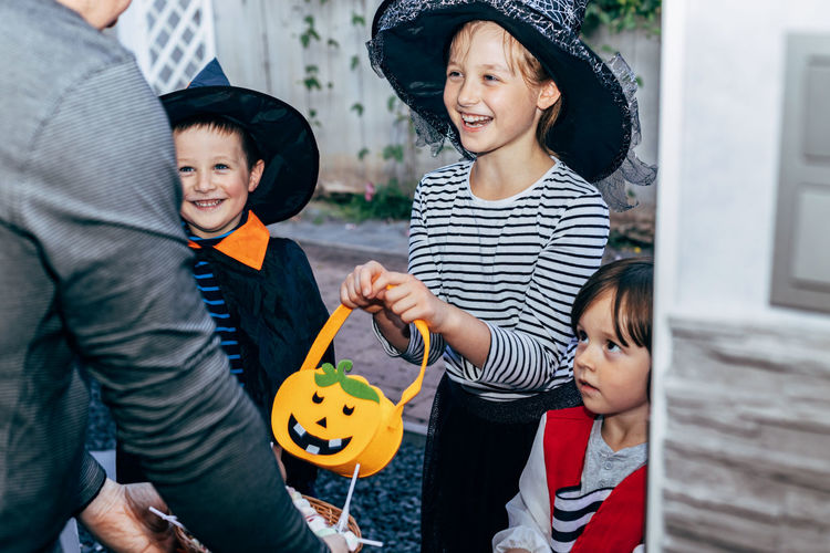 Close-up of a man handing out sweets to joyful children on halloween. children's tricks or treats. 