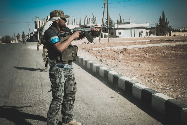 Terrorist holding rifle while standing on road