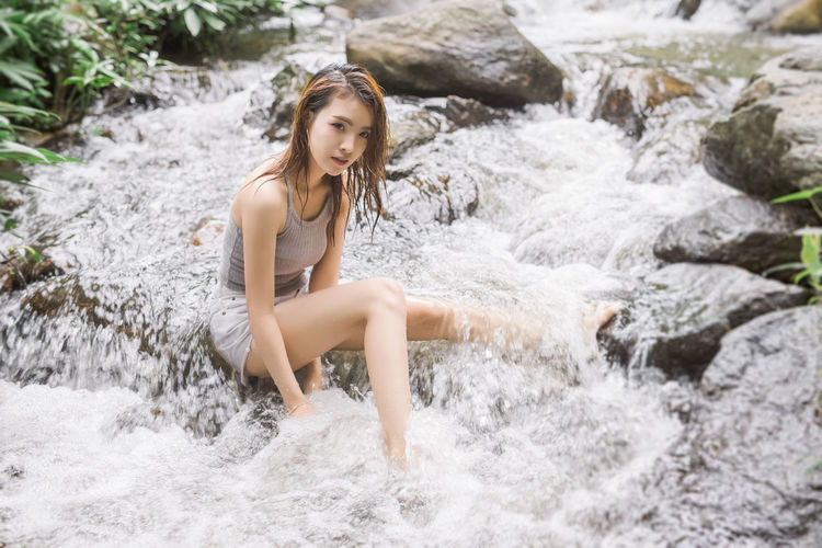 Alone beautiful young asian woman travel to visit waterfall forest in vacation trip at thailand.