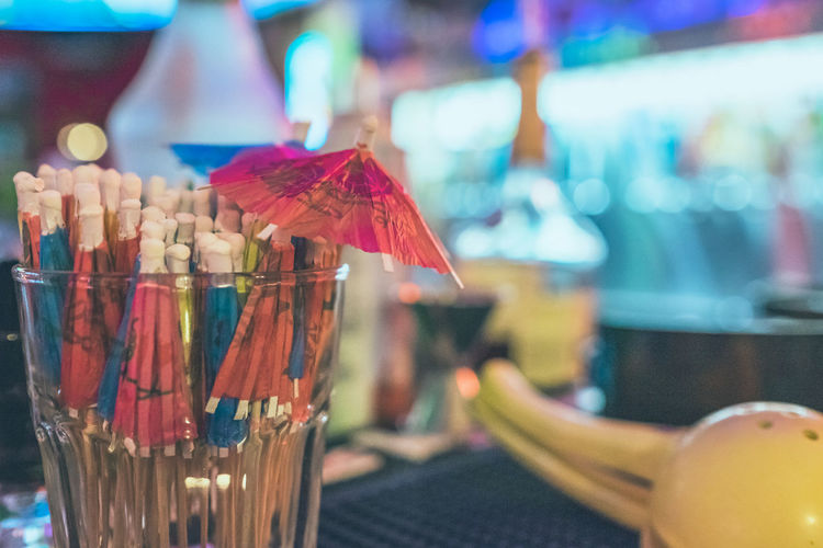 Close-up of drink umbrellas in glass on bar counter at nightclub