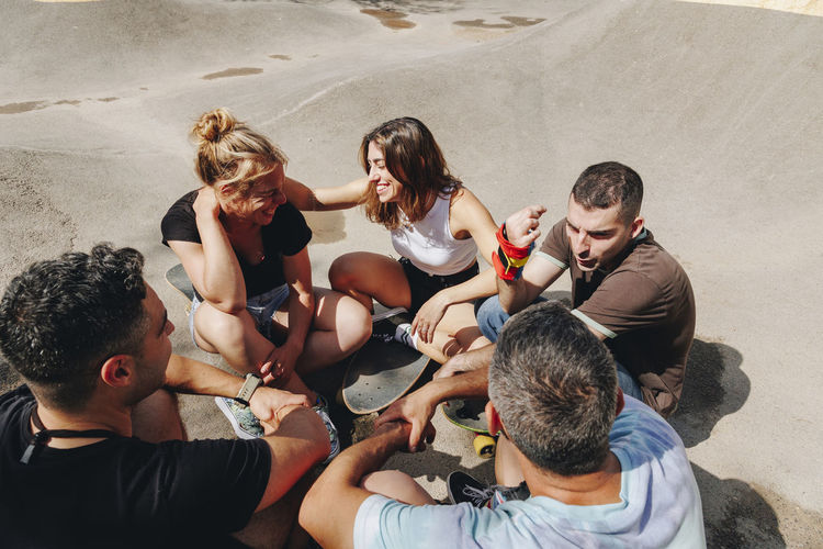 Happy friends talking with each other at skateboard park on sunny day
