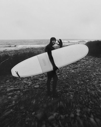 Side view of man holding surfboard at beach