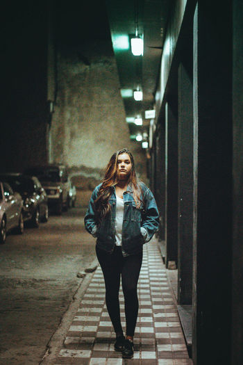 Portrait of woman standing by building at night