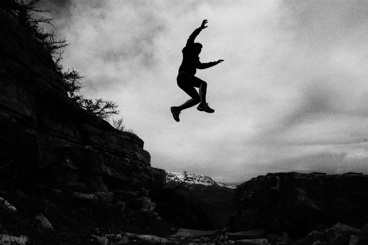 Low angle view of man jumping on rock