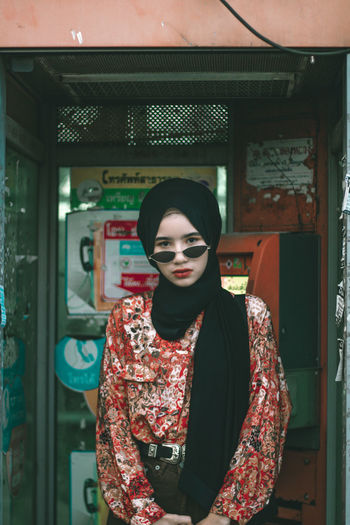 Portrait of girl standing in telephone booth 