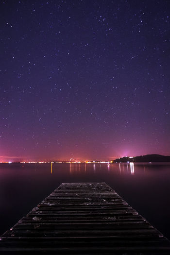 Scenic view of lake against clear sky at night with city lights in the background