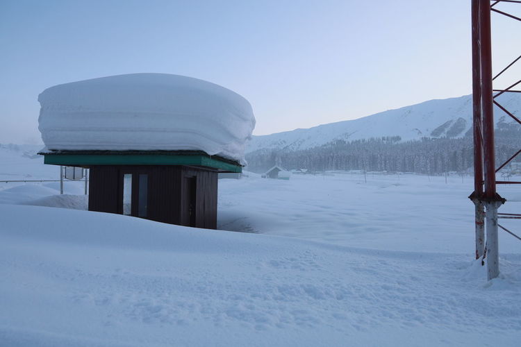 Built structure on snow covered mountain against sky